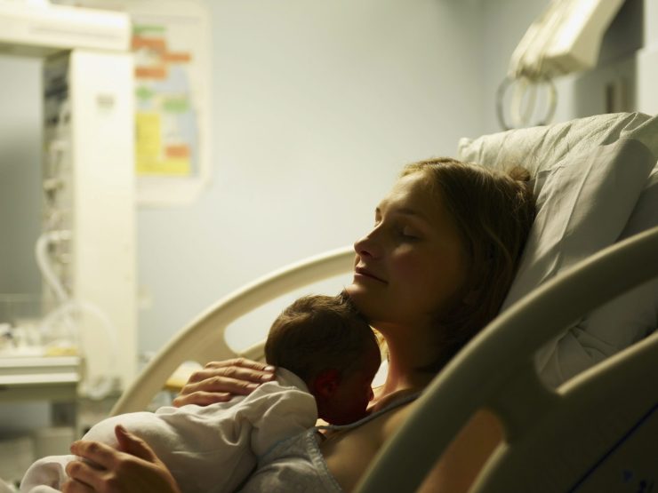 Mother holding newborn in hospital bed, serene and content atmosphere.