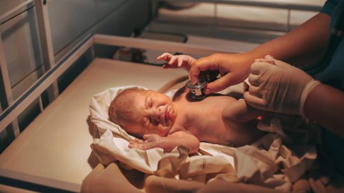 Doctor examining newborn with stethoscope, conveying professional care and medical vigilance.