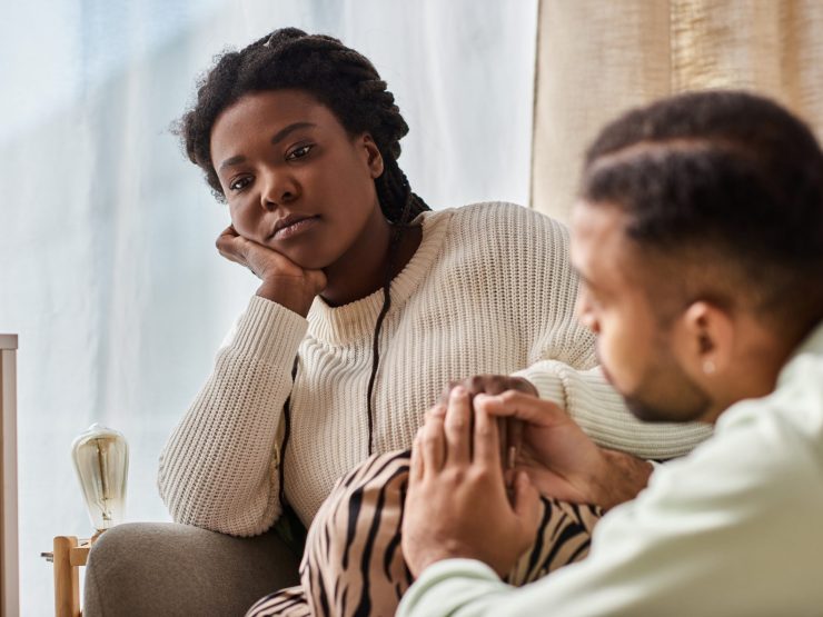 Worried woman consoled by her partner at home, conveying support and empathy.