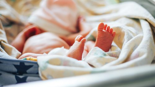 Newborn feet wrapped in blanket, symbolizing fragile care in medical contexts.