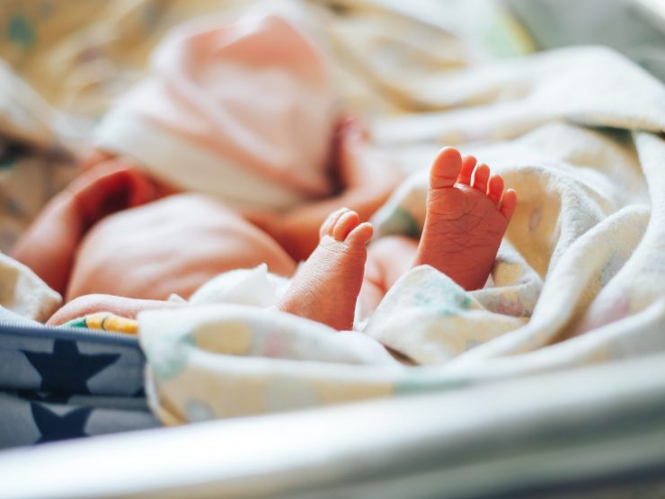 Newborn feet wrapped in blanket, symbolizing fragile care in medical contexts.
