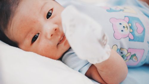 Infant resting peacefully on a white pillow, symbolizing vulnerability and care.