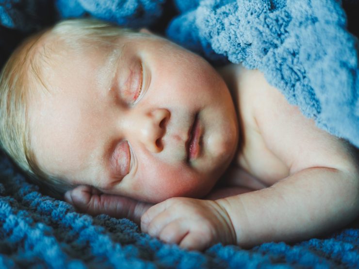 Infant peacefully sleeping, wrapped in a soft blue blanket.