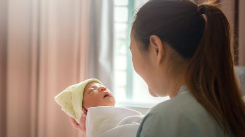 Mother peacefully holding newborn baby, symbolizing trust and care in medical settings.