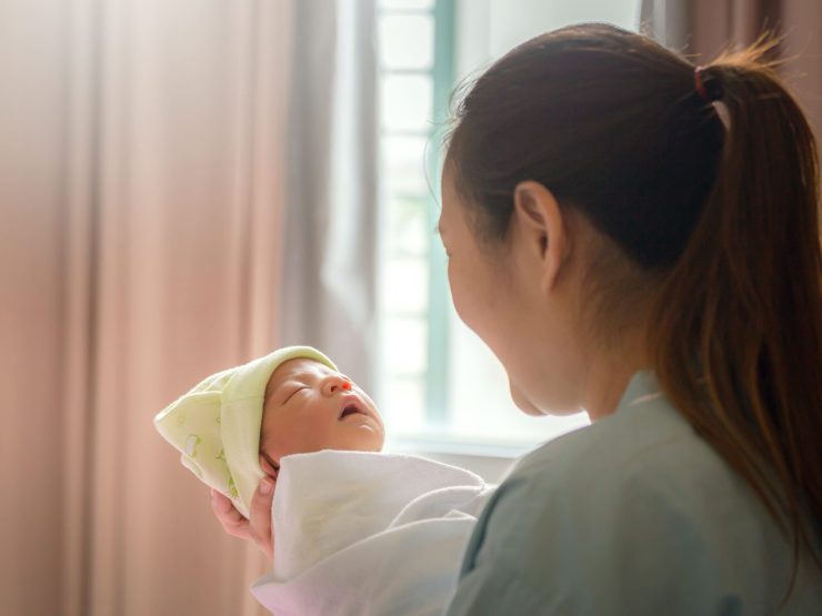 Mother peacefully holding newborn baby, symbolizing trust and care in medical settings.