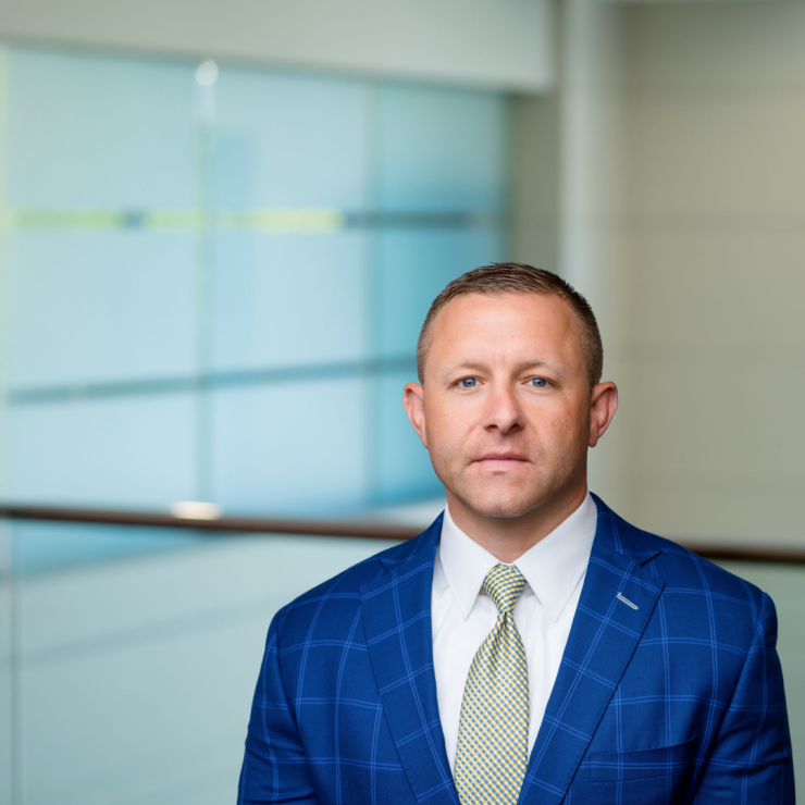 Professional man in a blue suit, serious expression, office setting background.