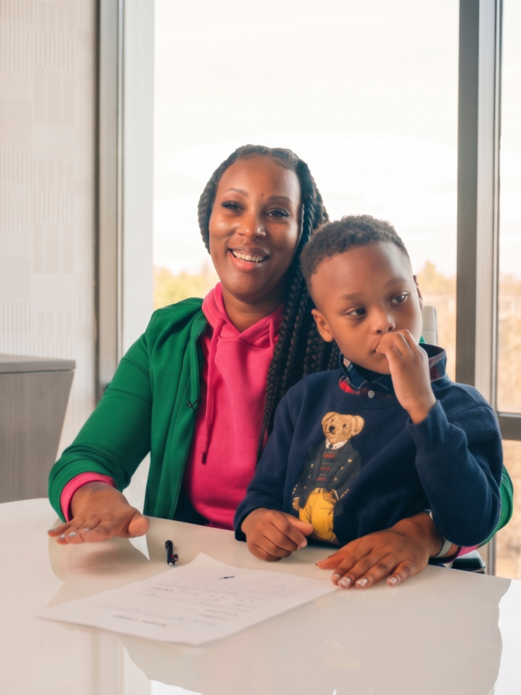 Smiling woman and child review documents in a modern office setting.