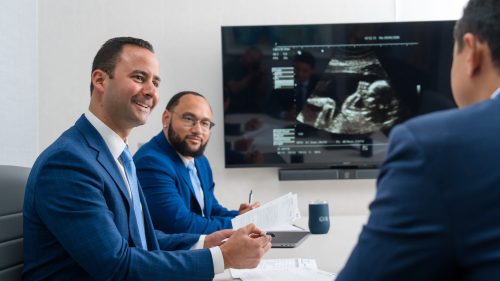 Lawyers discussing case with medical scan on screen, conveying professionalism and focus.