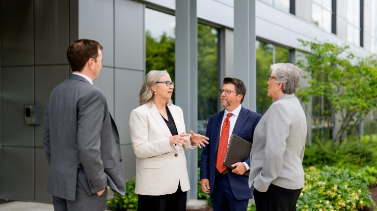 Four professionals discussing legal matters outside modern office building.