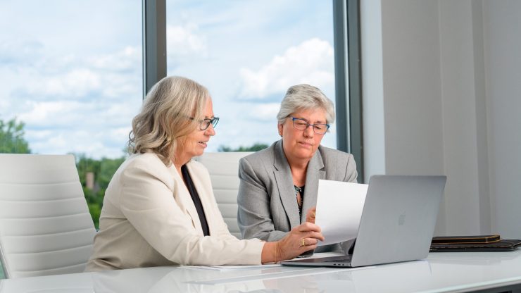 Two professionals discussing legal documents in a modern office setting.