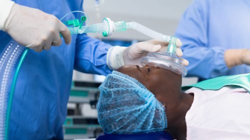 Surgeons administering anesthesia to a patient in a medical setting.