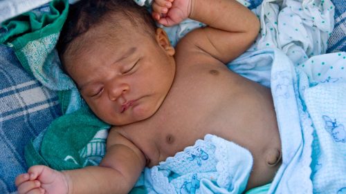 Sleeping infant nestled in a hammock, peaceful and serene setting.