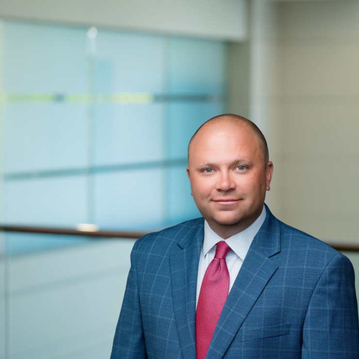 Professional in business suit with confident expression in a modern office setting.