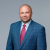 Professional attorney in suit and tie, confident expression, plain background.