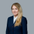 Professional woman with long hair in a navy suit, neutral expression.