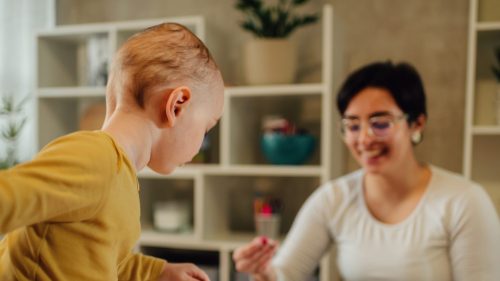 Child and adult engaging happily in arts and crafts activity.