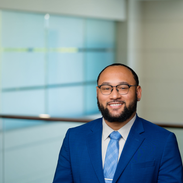 Smiling lawyer in blue suit, professional office background.