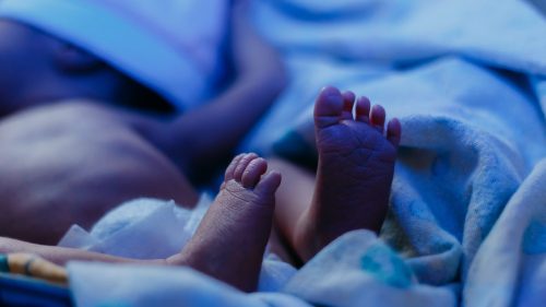 Infant's tiny toes nestled in soft blue blanket convey vulnerability and care.