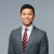 Smiling professional man in a suit against a neutral background.