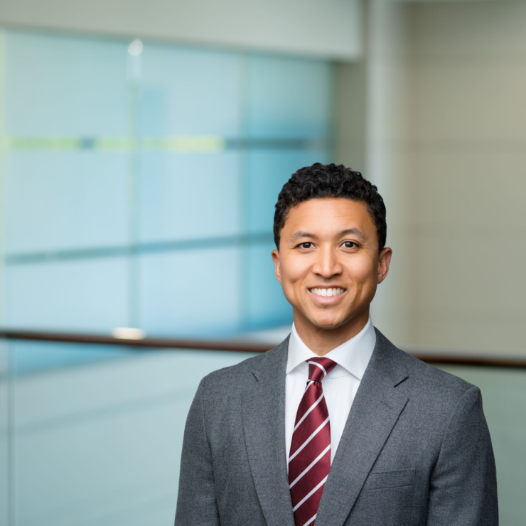 Smiling professional man in a suit, standing in a modern office setting.