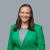 Smiling professional woman in a green blazer against plain background.