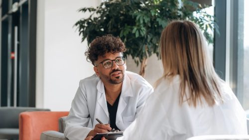 Medical professional attentively consulting with patient in a modern, bright office.