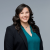 Professional woman in blazer smiling confidently against neutral background.