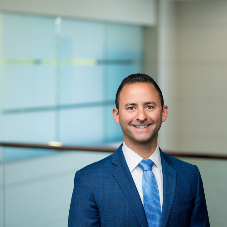 Smiling professional in suit against blurred office background, conveying confidence and professionalism.