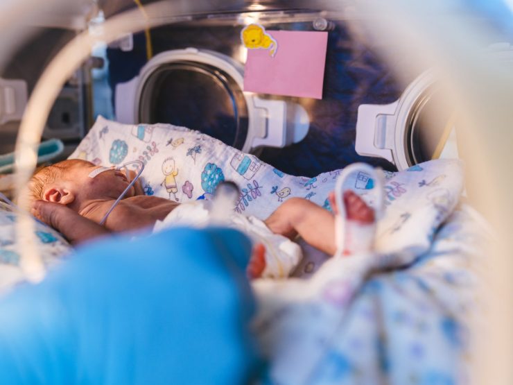 Newborn peacefully sleeping in a hospital incubator, symbolizing care and vulnerability.