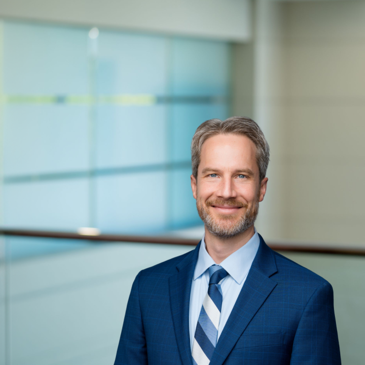 Smiling professional in suit against modern office backdrop, conveying trust and expertise.