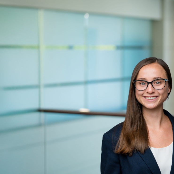 Professional woman in a suit smiling in a modern office setting.