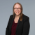 Professional woman smiling confidently in a blazer, conveying competence and approachability.