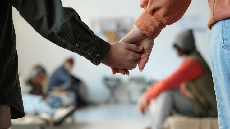 Couple holding hands supportively in a medical waiting room environment.