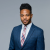 Professional man in suit, confident expression, formal business attire, neutral background.
