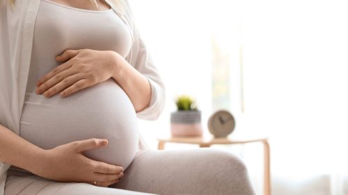 Pregnant woman gently holding belly, emphasizing care and reassurance.