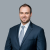 Professional attorney in suit smiling against plain background.